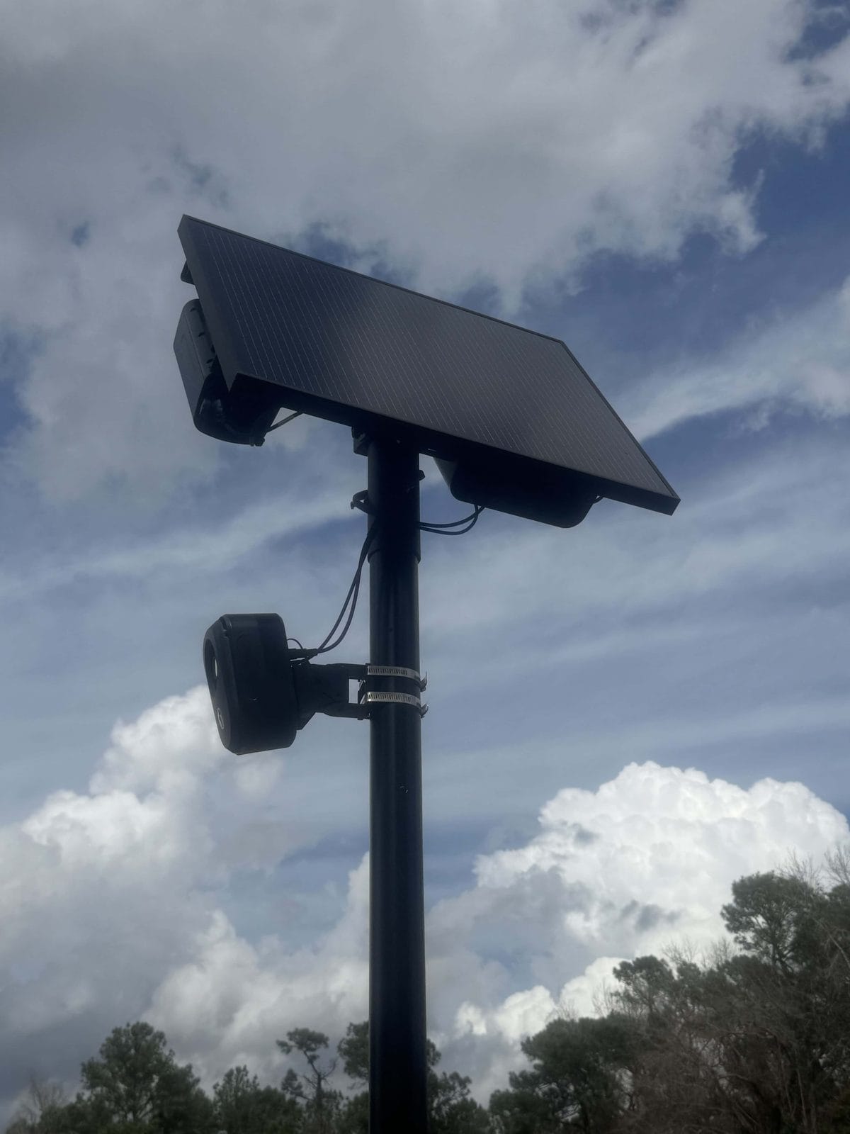 A solar-powered Flock automated license plate reader camera on a pole against a blue sky in New Hanover County, North Carolina.